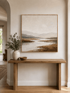 Neutral hand-painted mountain wall art displayed above an entryway console in a warm contemporary interior
