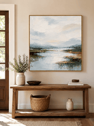 Neutral blue river landscape wall art displayed above an entryway console in a modern home