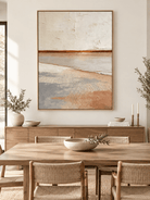 Vertical textured coastal landscape wall art displayed in an open dining room with natural wood and stone furniture
