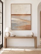 Large vertical neutral coastal wall art displayed above an entryway console in a wabi-sabi interior
