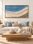 Large blue ocean wave painting displayed above a cream sofa in a modern coastal living room
