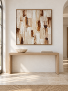 Square beige and brown wabi-sabi wall art displayed above an entryway console in a neutral modern interior