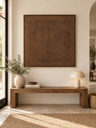 Square brown textured wall art displayed above an entryway console in a minimalist wabi-sabi interior