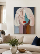 Geometric woman portrait above a neutral sofa in a contemporary living room