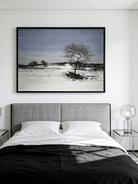  Large horizontal hand-painted minimalist oil painting of a single dark tree in a vast white snowfield under a soft blue sky.