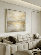 Large square hand-painted gold and white abstract painting with metallic drip texture by Evelyn Li in a luxury living room setting.