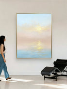 Large vertical hand-painted impressionist sunset seascape in pastel pink and blue with golden light reflections by Evelyn Li in a minimalist bedroom.