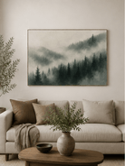 Misty pine forest painting displayed above a neutral sofa in an organic modern living room