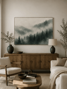 Misty pine forest painting displayed above a neutral sofa in an organic modern living room