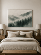 Foggy evergreen forest wall art displayed above the bed in a calm Scandinavian-style bedroom