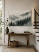 Horizontal neutral forest painting displayed above a long wood console in a modern entryway