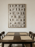 Close-up of hand-painted 3D relief wall art, featuring raised oval stone-like textures in warm beige plaster on a large canvas for a minimalist bedroom.