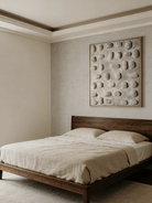 Close-up of hand-painted 3D relief wall art, featuring raised oval stone-like textures in warm beige plaster on a large canvas for a minimalist bedroom.