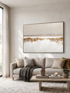 Large horizontal textured cream and gold abstract canvas wall art above modern neutral sofa in living room