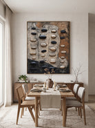 Framed vertical textured plaster stone wall art mounted in modern dining room with natural wood accents