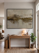 Framed textured marsh landscape painting styled above a natural wood console table in a bright entryway