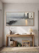 Rustic coastal house canvas painting with golden light reflection above entryway console table