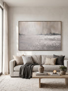 Large horizontal neutral winter landscape canvas wall art above modern sofa in minimalist living room