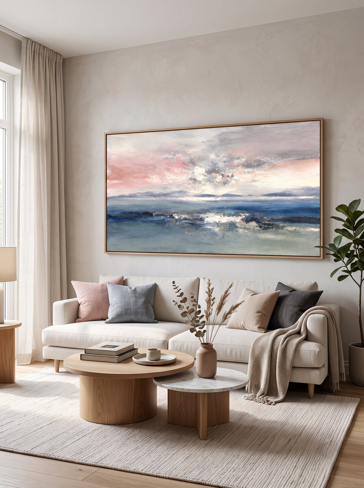 Abstract coastal seascape painting with blush pink and blue tones displayed above a sofa in a modern living room.
