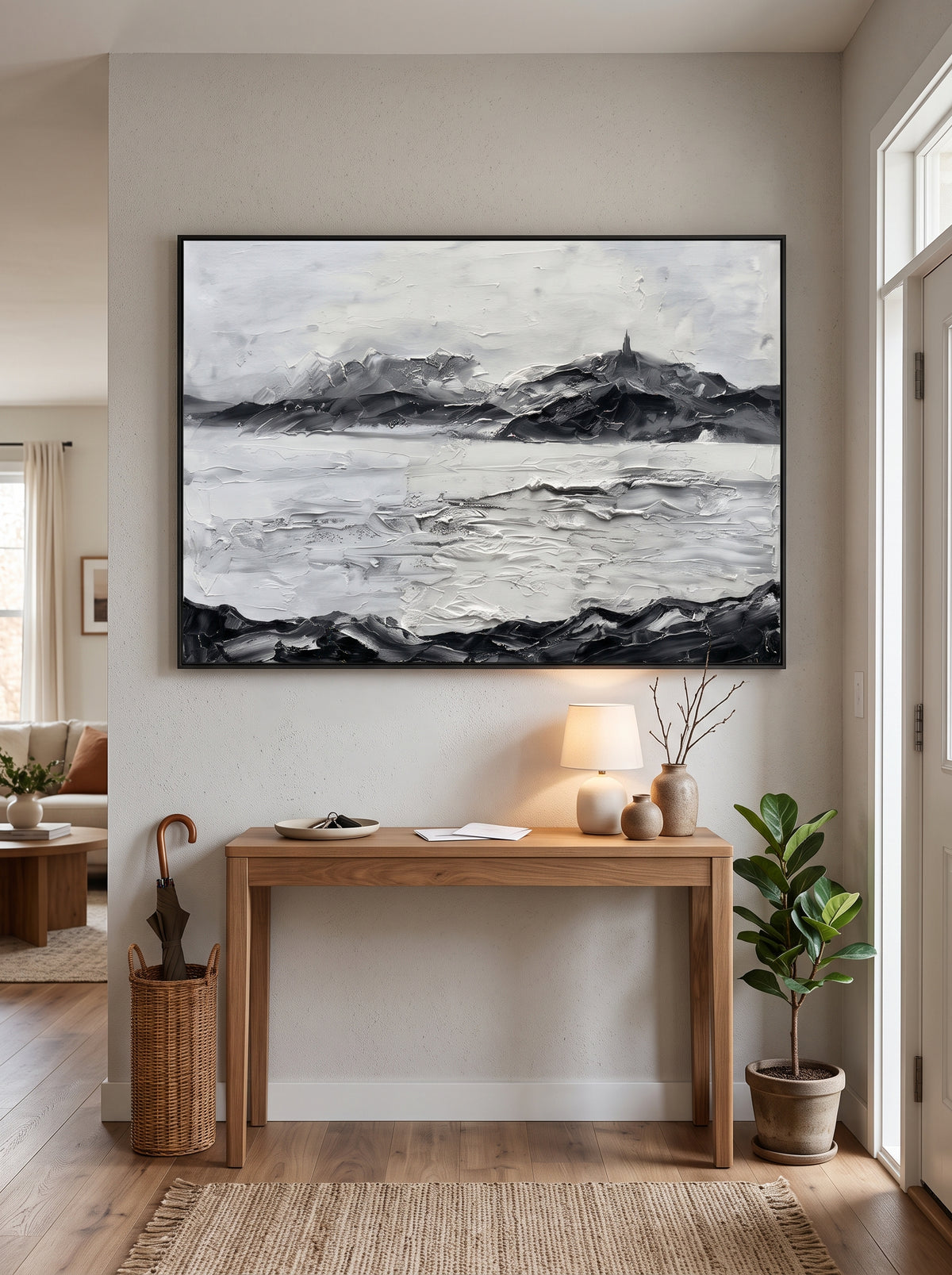 Framed textured winter mountain landscape painting styled above a wooden console table in a contemporary entryway