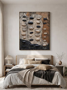 Tactile black and white pebble relief painting by Eliot Vermeer hanging in calming wabi-sabi neutral bedroom