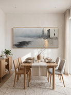 Framed textured horizontal winter lake artwork displayed in open-concept dining room with wood furniture