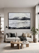 Oversized horizontal black and white textured mountain landscape painting mounted above a modern neutral sofa