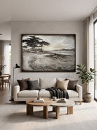 Oversized horizontal black and white textured pine tree landscape painting mounted above a modern neutral sofa