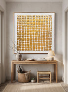 Sculptural warm gold relief canvas painting mounted above minimalist console table in Japandi entryway