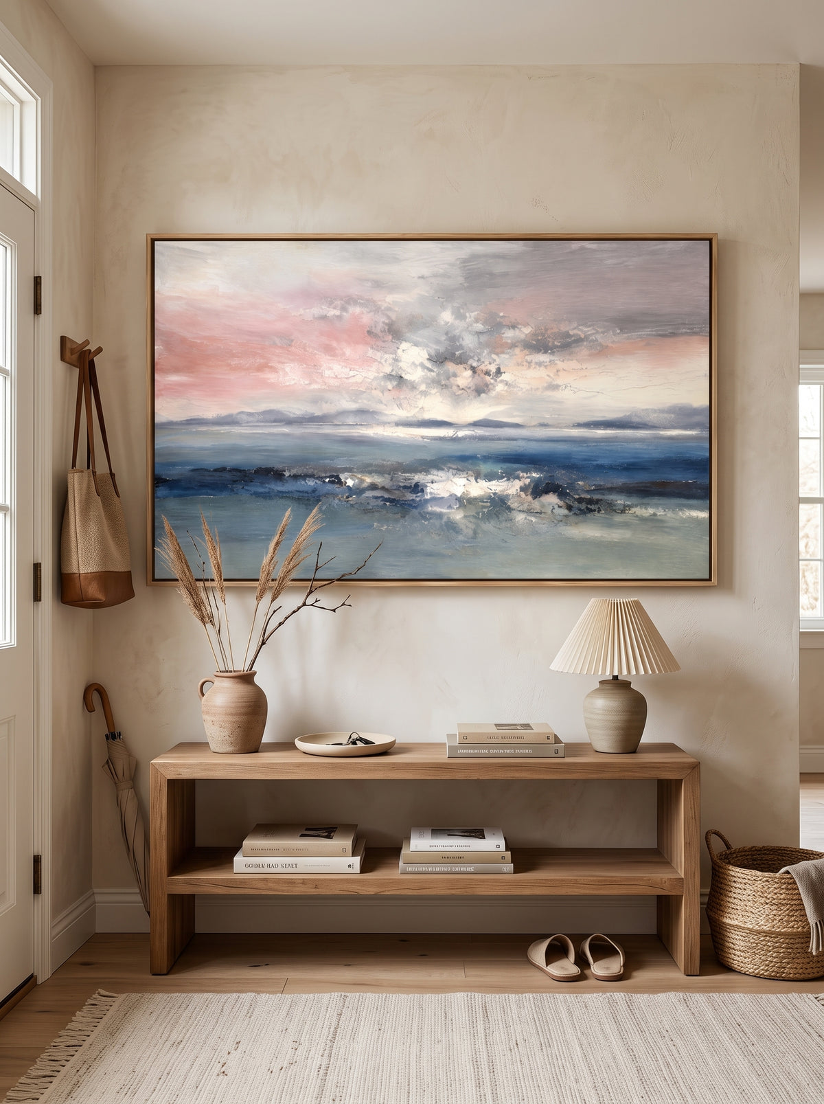 Abstract coastal wall art with soft blue ocean and blush sky displayed in a bright modern entryway.