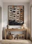 Sculptural neutral pebble relief canvas art hung above wooden console table in contemporary Japandi entryway
