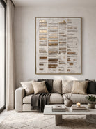 Vertical distressed metallic gold 3D relief canvas art displayed next to modern neutral sofa in wabi-sabi living room
