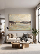 Oversized horizontal soft neutral lake landscape painting mounted above a contemporary living room sofa