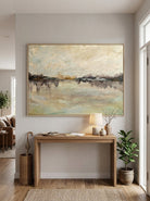Framed peaceful lake landscape painting styled above a wooden console table in a bright modern entryway