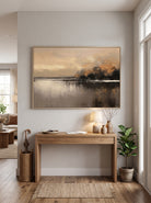 Framed textured dusk waterscape painting styled above a wooden console table in a contemporary entryway