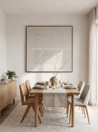 Framed off-white textured relief panel artwork displayed in bright open-concept dining room with wood table