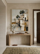 Vertical textured village architecture painting styled above a wooden entryway console table