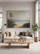 Oversized horizontal neutral coastal beach landscape painting mounted above a contemporary living room sofa