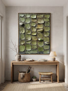 Sculptural sage green relief canvas painting hung above wooden console table in contemporary Japandi entryway
