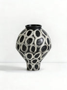 hand-painted black and white abstract ceramic vase with circular patterns, contemporary sculptural vase on a minimalist console.
