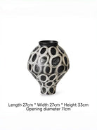 hand-painted black and white abstract ceramic vase with circular patterns, contemporary sculptural vase on a minimalist console.