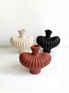 sculptural fluted ceramic vases in black, cream, and terracotta rust, organic heart-shaped silhouette, artistic home decor.