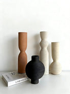 ribbed geometric ceramic vases in black, sand, and terracotta, minimalist organic pottery for shelf styling.