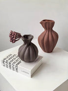 artisan biomorphic ceramic vases with twisted ridge textures, earthy terracotta and basalt grey sculptural pottery on a white surface.