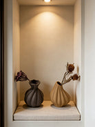 artisan biomorphic ceramic vases with twisted ridge textures, earthy terracotta and basalt grey sculptural pottery on a white surface.