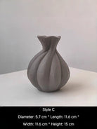 artisan biomorphic ceramic vases with twisted ridge textures, earthy terracotta and basalt grey sculptural pottery on a white surface.