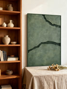 Black and green abstract textured river canvas art displayed on a modern living room wall