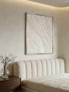 Close-up of the hand-painted white textured wall art featuring heavy impasto waves and mineral textures in a modern silver floater frame.