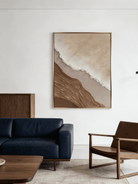 Close-up of a hand-painted 3D textured abstract beach painting featuring heavy wave-like ridges in sand beige and ochre in a gold frame.