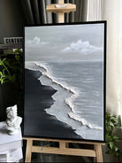 Close-up of a hand-painted 3D textured black sand beach painting with heavy white sculpted seafoam and black waves in a black frame.